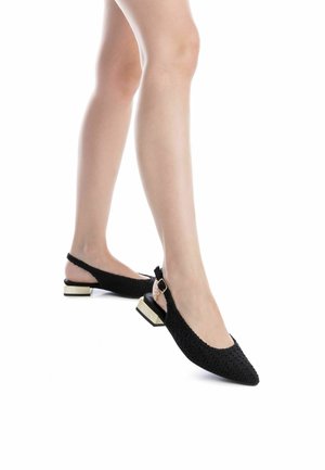 Zapatos negros de tacón bajo tipo slingback con textura trenzada, punta afilada y tacón bajo con detalles en dorado. Correa ajustable para un mejor ajuste.