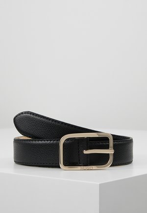 Black textured leather belt with gold rectangular buckle engraved with "HUGO," coiled on a white surface against a plain gray background.