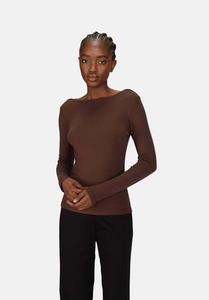 Haut long en marron avec un décolleté bateau, fabriqué en tissu texturé, au design ajusté, avec des accents pour les pouces, associé à un pantalon noir.