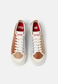 Mångfärgade sneakers med en ovandel i vit, brun och ljusblå läder. Har krämfärgade snören, röda innersulor och markerade vita gummisulor.