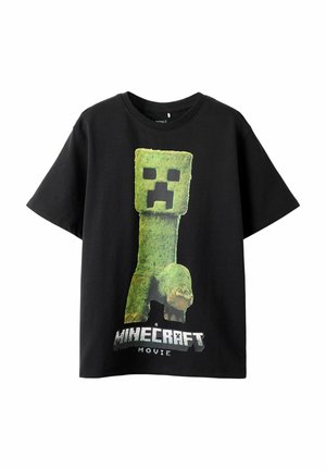 Black cotton t-shirt featuring a large green cube character with a frown and claws, printed text below reads "A Minecraft Movie."