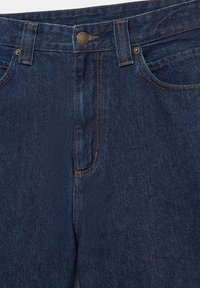 Mørkeblå denimjeans med metal knap, bæltestropper og synlig orange syning omkring lommer og sømme.