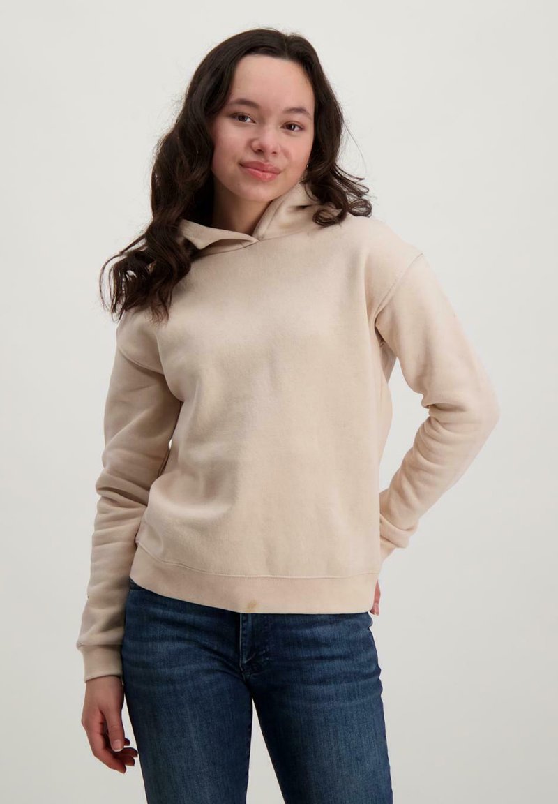 Beige hoodie met een voorzak, trekkoordkap en geribde manchetten. Draagt met blauwe jeans, die een gladde textuur hebben.