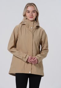 Beige wasserdichte Jacke mit Kapuze, vorderem Druckknopfverschluss und verstellbaren Manschetten. Verfügt über eine entspannte Passform und eine glatte Textur.