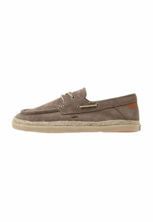 Chaussure bateau décontractée en daim marron avec détails tressés sur la semelle, laçage sur le devant et patch beige au talon, vue de côté sur fond blanc.