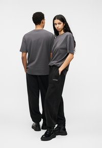 Γκρι βαμβακερά μπλουζάκια με κοντά μανίκια, σε συνδυασμό με μαύρο φόρμα παντελόνι με πλαϊνές τσέπες και ελαστικά μανσέτες. Μαύρα χοντρά μποτάκια ολοκληρώνουν την εμφάνιση.