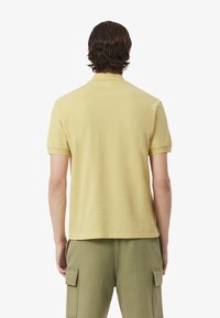 Geel poloshirt met korte mouwen, een klassieke kraag, een gladde textuur en een rechte snit, gecombineerd met lichtgroene cargobroek.