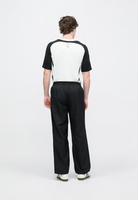 Čierno-biele športové oblečenie so sfarbeným krátkym rukávom a voľnými čiernymi nohavicami. Tenký, nastaviteľný pás.