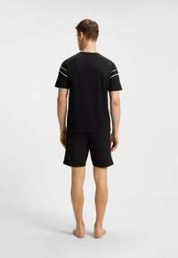 Black athletic t-shirt with short sleeves and contrasting shoulder stripes; paired with black shorts. Smooth fabric, minimal design.