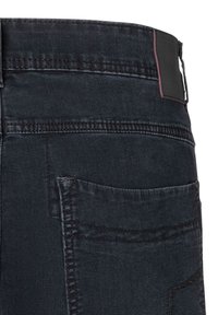 Dark denim jeans featuring a slim fit, contrasting stitching, and a back pocket. Black waistband with subtle logo detail.
