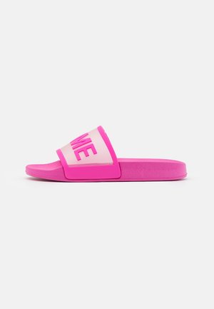 Sandale slide rose vif avec une large bride ornée de lettres en relief sur un fond rose clair, vue de profil sur une surface blanche.