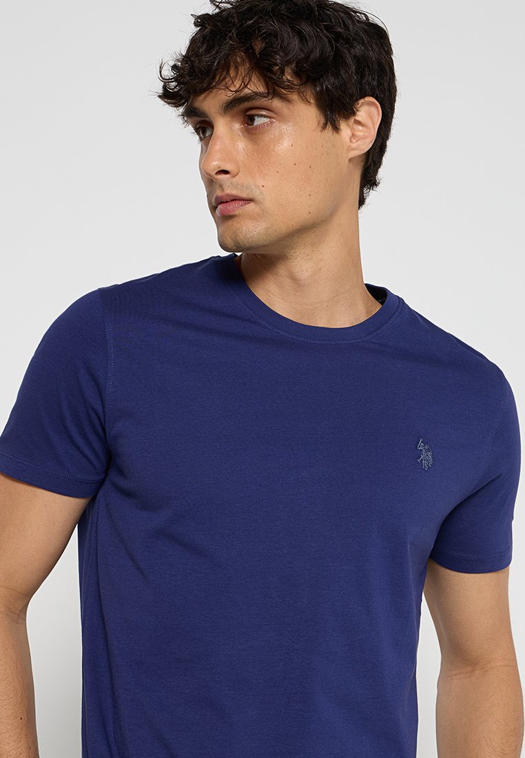Navyblaues Kurzarm-T-Shirt aus Baumwollmischung mit Rundhalsausschnitt und dezentem gesticktem Logo auf der Brust. Glatte Textur.