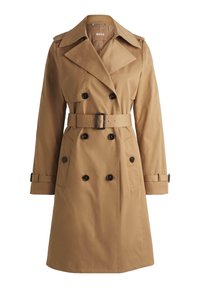 Trench-coat beige croisé avec un large col, boutons noirs, ceinture à la taille et brides boutonnées aux manches, étiqueté BOSS à l’intérieur du col.