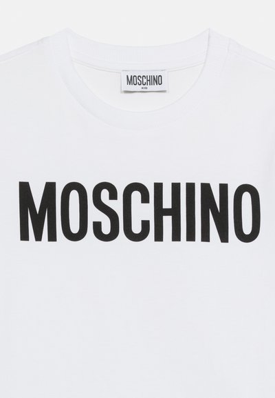 Άσπρο παιδικό T-shirt Moschino με έντονο μαύρο κείμενο "MOSCHINO" τυπωμένο στο στήθος και ετικέτα με το ίδιο όνομα επωνυμίας μέσα στο γιακά.