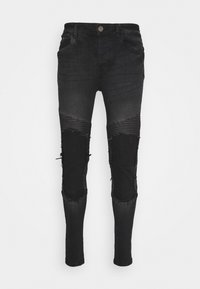 Black denim skinny jeans with ribbed panel accents, distressed knee areas, and a fitted shape. Features standard pockets and button closure.
