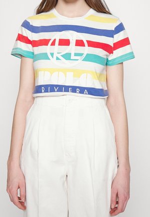 Osoba ubrana w krótki, wielokolorowy t-shirt w paski z napisem "RL POLO RIVIERA" i wysokowystające białe spodnie.