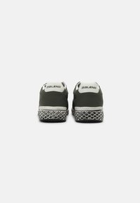 Green athletic shoes with a smooth upper, white accents, and a textured black sole featuring a diamond pattern.