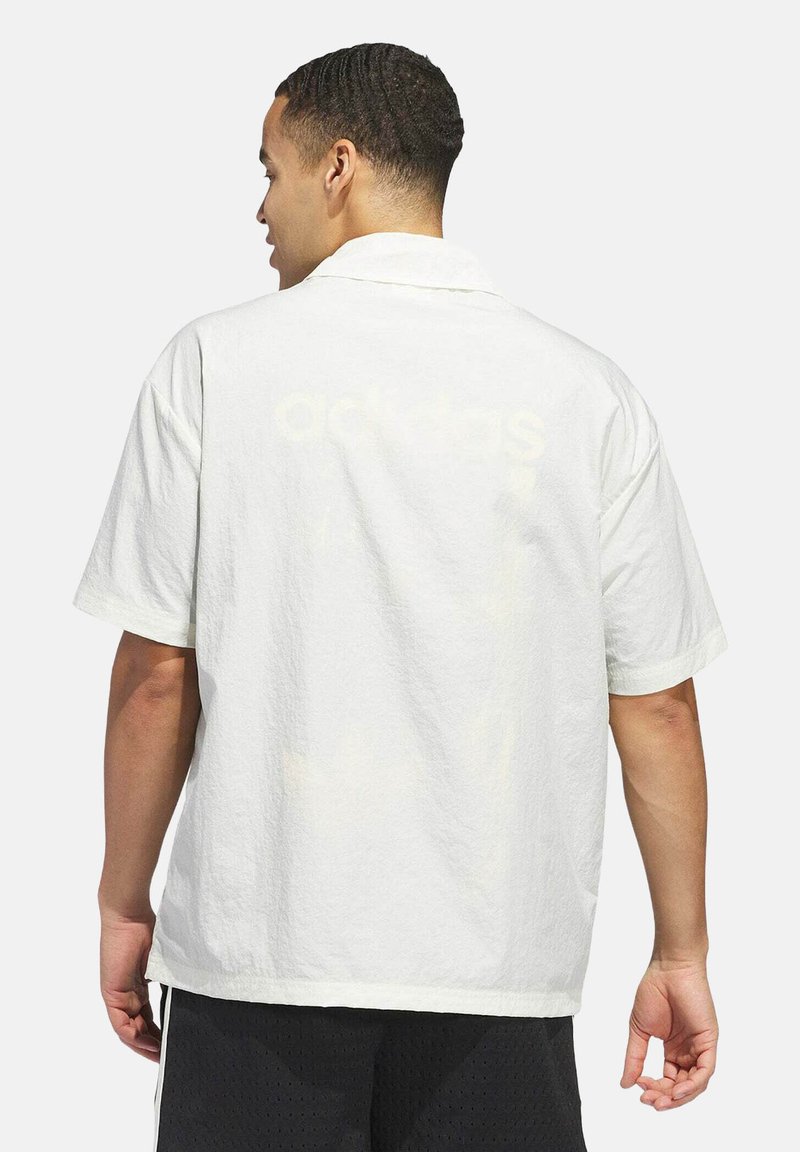 Camicia bianca a maniche corte con tessuto strutturato, caratterizzata da un logo discreto stampato sul retro e una vestibilità rilassata.