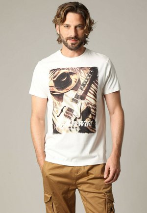 Witte katoenen t-shirt met een graphic print van een elektrische gitaar en een hoed, met een verouderde uitstraling en de tekst "Wild & Free" eronder.