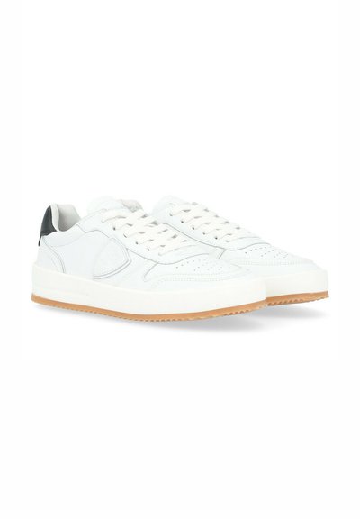 Sneaker bianche in pelle con una texture liscia, dotate di perforazioni sulla punta, lacci piatti e un accento nera sul tallone. Suola in gomma naturale.