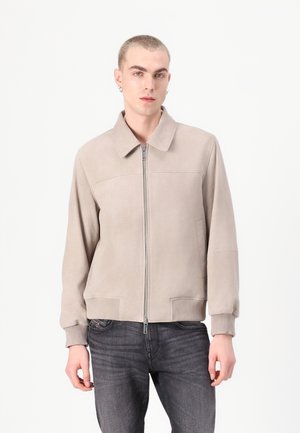 Beige suede bomber jacket with a point collar, front zipper, ribbed cuffs, and two side pockets. Features a smooth texture and minimal design.