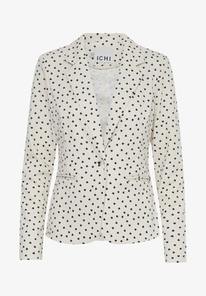 Blazer en tissu crème avec un motif de cœurs noirs à pois. Il dispose d'un col à revers, de deux poches avant et d'une fermeture à un seul bouton.