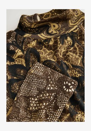 Brun ribbad topp med hög krage som har en strukturerad, mönstrad design i nyanser av guld och svart, som påminner om ormskinn.