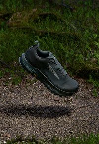 Încălțăminte sportivă verde închis, cu un overlay texturat, talpă din cauciuc și amortizare pronunțată. Prezintă un logo pe lateral și un toc întărit.
