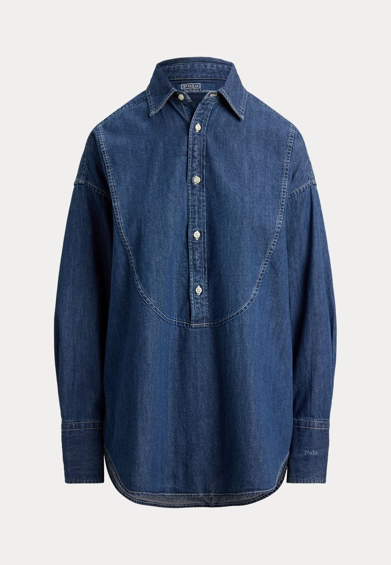 Camicia di denim di colore blu scuro, con chiusura frontale con bottoni, colletto a punta, maniche lunghe e dettaglio unico con yoke curvo sul retro.