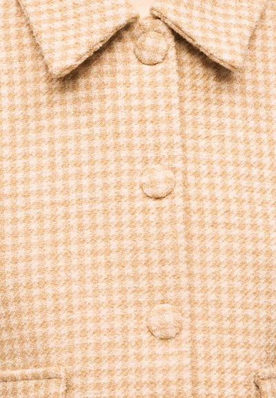 Manteau en laine beige et blanc à motif pied-de-poule, avec des boutons recouverts de tissu et un col pointu.