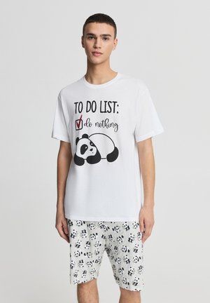 Maglietta bianca in cotone con grafica di un panda e testo; abbinata a pantaloncini grigio chiaro con motivo panda. Vestibilità comoda.