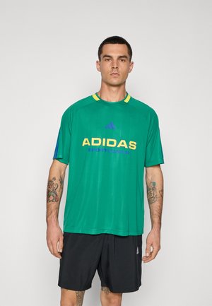 Zielona koszulka sportowa z niebieskimi i żółtymi akcentami, z logo "ADIDAS SPORTSWEAR" w odważnym żółtym i fioletowym, wykonana z oddychającego materiału.