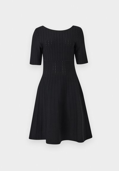 Μαύρο φόρεμα μέχρι το γόνατο με κοντά μανίκια, εφαρμοστή μέση και κάθετο σχέδιο με τρύπες σε όλο το ύφασμα.
