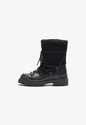 Bota preta que combina couro liso e fleece texturizado, com uma sola robusta, detalhes de atacador e um alto colar de fleece para aquecer.