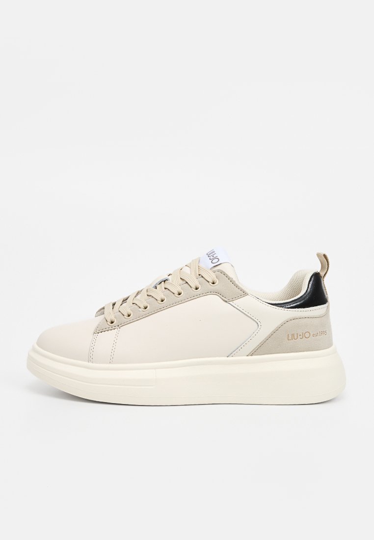 Beżowe skórzane sneakersy o teksturowanym wykończeniu, płaskiej podeszwie, sznurowanym przodzie i kontrastującym czarnym akcentem na pięcie. Logo marki na języku.
