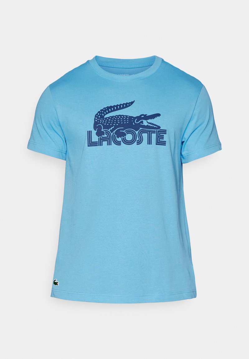 Lichtblauwe katoenen T-shirt met een marineblauw krokodillenlogo en de tekst "LACOSTE". Korte mouwen en een ronde halsstijl. Subtiele textuur.