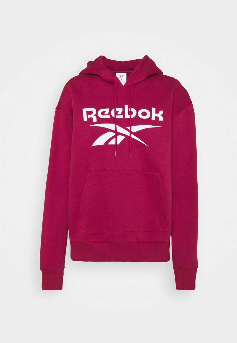 Maroon hoodie med en framficka, ribbad mudd och fåll, med en stor vit Reebok-logga på bröstet. Mjuk, strukturerad ibland.