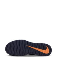 Semelle de chaussure Nike en caoutchouc noir avec un motif texturé, mettant en avant un accent en swoosh orange. La forme est ergonomique avec un profil légèrement courbé.