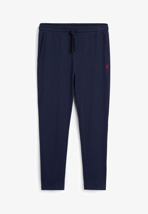 Pantalons de survêtement bleu marine avec une taille élastique, un cordon de serrage et des poches latérales. Présente un petit logo rouge sur la jambe gauche. Texture douce.