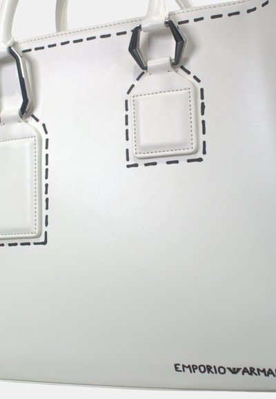 Borsa tote bianca con accenti di cucitura nera, dotata di due etichette rettangolari e accessori in contrasto. Finitura liscia e opaca.