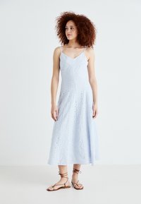 Rochie midi de culoare albastru deschis, cu bretele subțiri, având un model brodat și detalii cu găuri în formă de ochi. Material moale cu o siluetă fluidă, în formă de A.