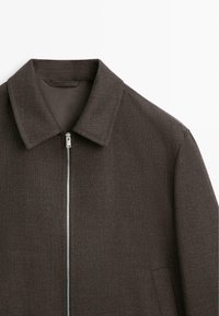 Giacca in lana marrone con cerniera frontale argentata, collo classico e tasche laterali su sfondo bianco.