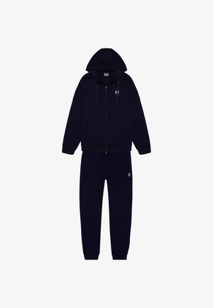 Felpa con zip color blu navy, con cordini, tasche laterali e pantaloni abbinati. Realizzata in tessuto morbido, con una toppa logo sul petto e sulla gamba.