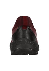 Chaussure de sport bordeaux et noire avec une tige synthétique texturée, un col rembourré et une semelle noire avec des éclats roses.