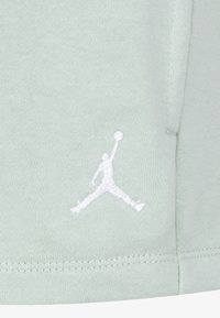 Lys grønn sweatshirt-stoff med en glatt tekstur. Har en hvit brodert Jumpman-logo og synlige sømmer.