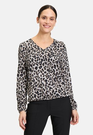 Blouse met luipaardprint in lichte stof, met een V-hals, lange mouwen en een zwart-beige kleurenschema. Getailleerde pasvorm bij de taille.