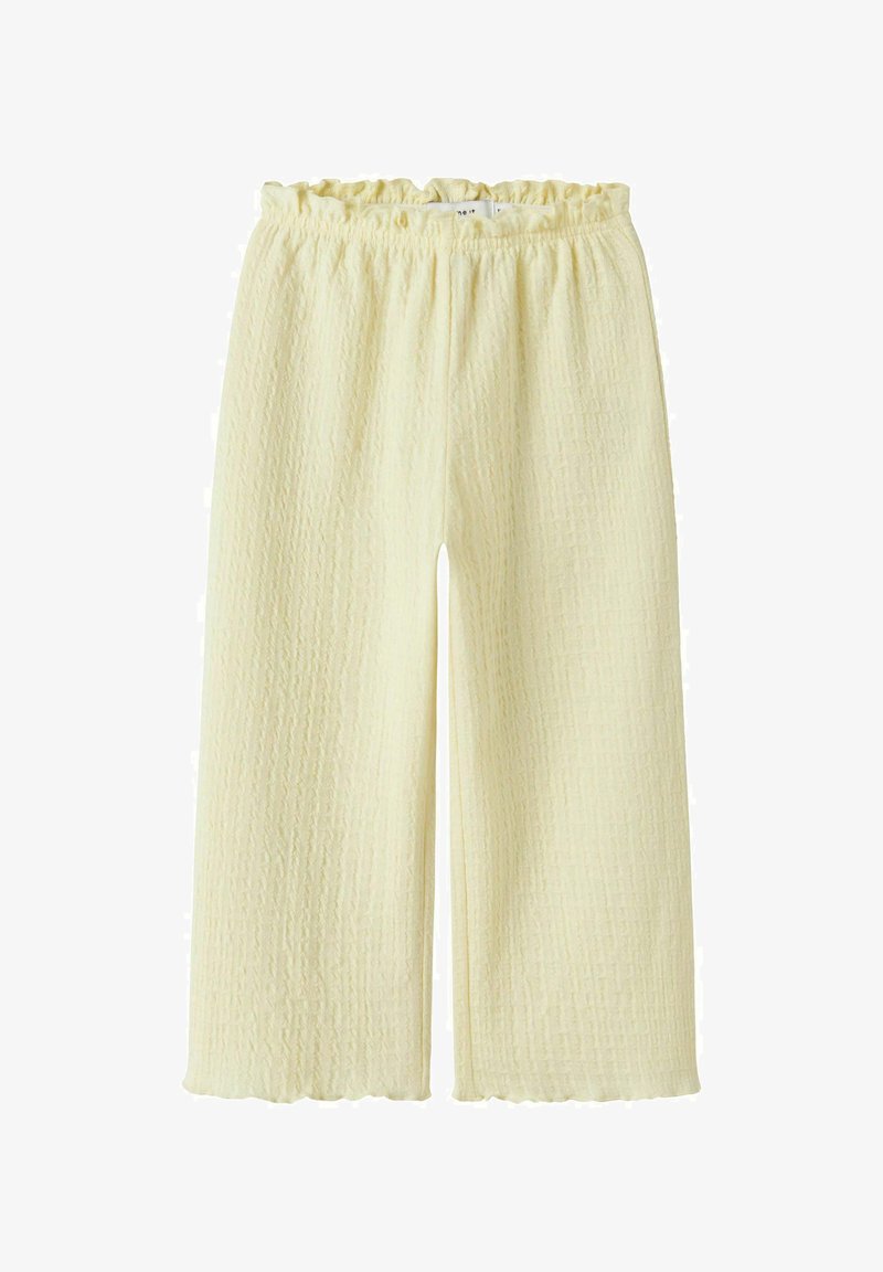 Kremfargede, teksturerte vide bukser med elastisk midjebånd og en lett rynket kant på en hvit bakgrunn.