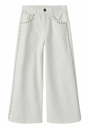 Fehér, bő szárú nadrág fém szegecsekkel az elülső zsebek mentén és a külső varrásoknál, gombos rögzítéssel és övbújtatókkal.