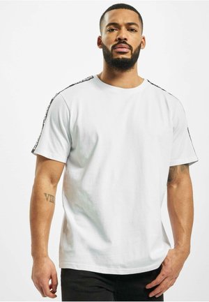 Hvid bomulds t-shirt med korte ærmer. Har sorte detaljer langs skuldrene. Rund halsudskæring, afslappet pasform og glat tekstur.