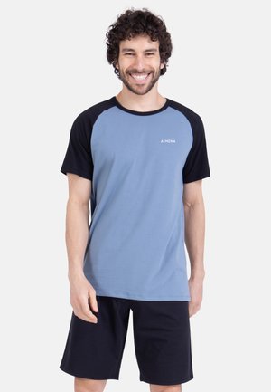 T-shirt bleu et noir avec manches raglan courtes, présentant un design uni et le mot "ATHENA" imprimé sur le devant. Se marie bien avec un short noir.